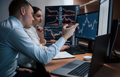 Active talking. Team of stockbrokers are having a conversation in a office with multiple display screens.