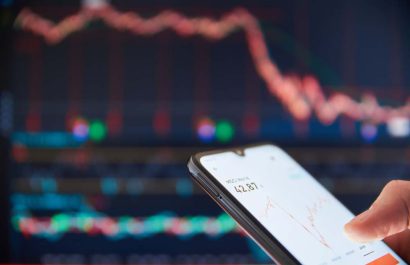 Investor analyzing stock market investments on a smartphone. Person trading stocks on a smartphone. Falling share prices at the stock exchange. Stock market crash. Trader at the stock exchange.