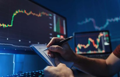 No face image of male hands writing numbers in notepad after analyzing diagram of crypto currency market at his pc, predicting patterns of money flow, inventing new strategy avoiding high risks