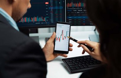 Focusing on phone with discussing dynamic stock market in two business traders online website compare with pc screens in real time currency rate investment on risk data at modern office. Postulate.